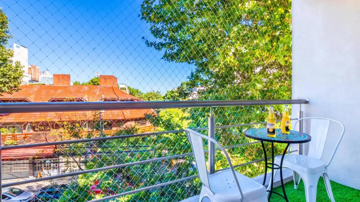 Balcón con mesa y sillas y vista a los árboles de Palermo